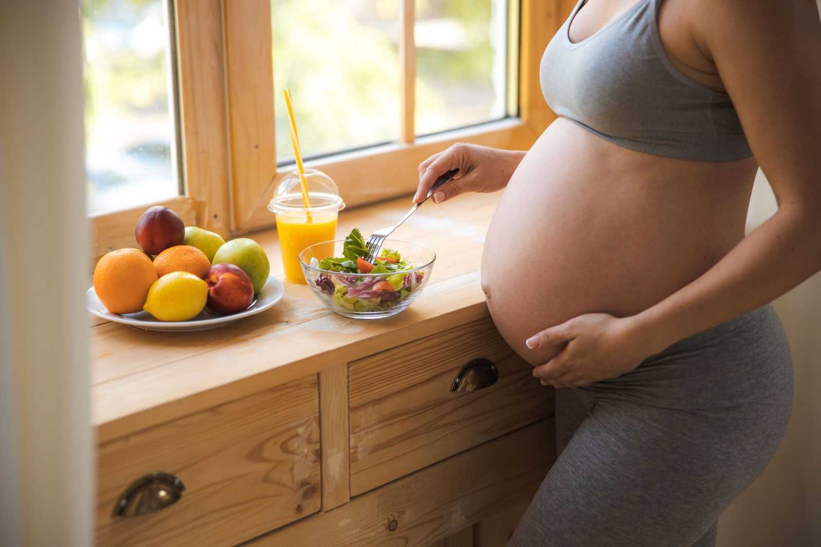 Pregnant lady eating healthy food at home