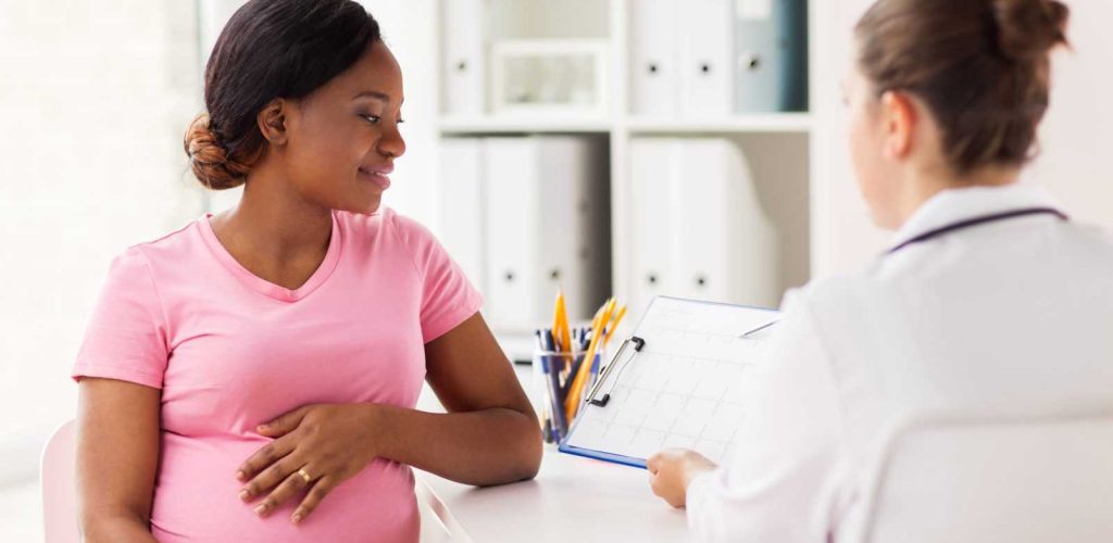 pregnancy, medicine, healthcare and people concept - cardiologist doctor showing cardiogram to pregnant african american woman meeting at hospital