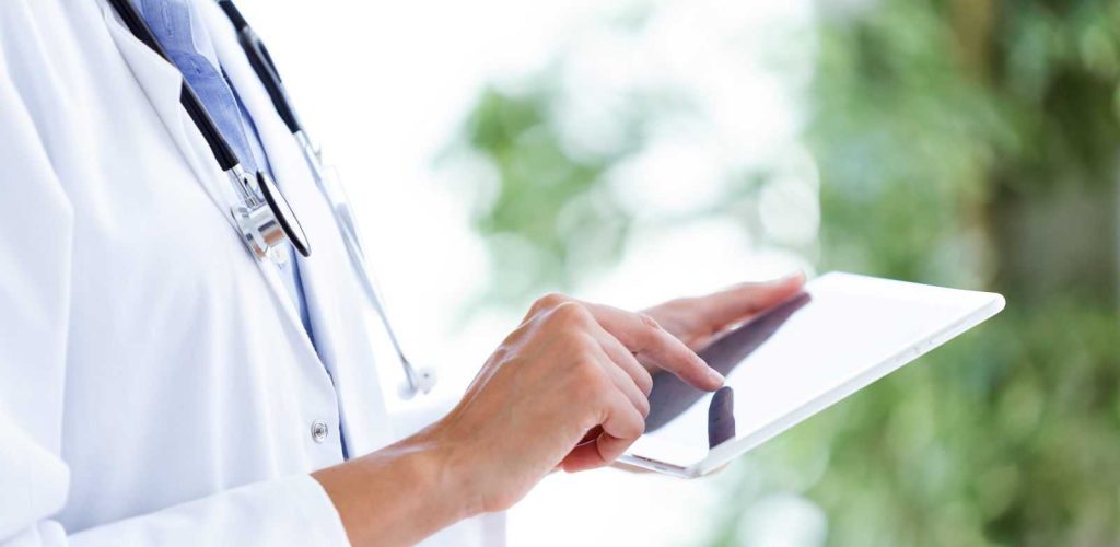 Close-up of female doctor using her digital tablet in the consultation.