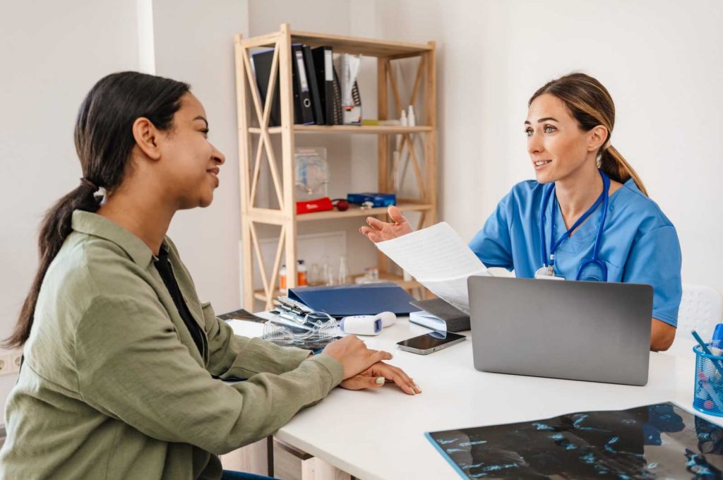 White woman doctor talking with patient while working in her office indoors